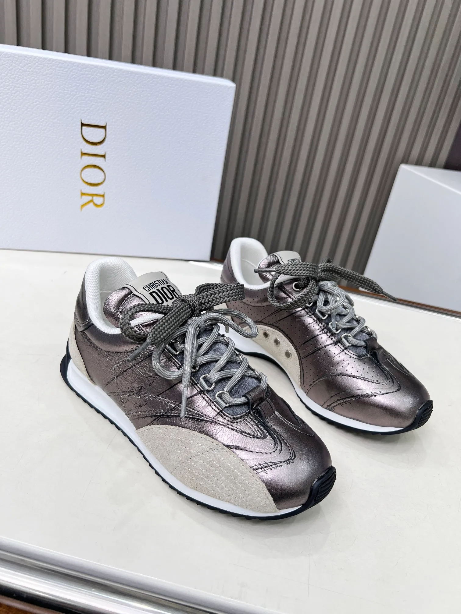 👟👟Ex-factory price 560👟👟 This D-Sketch sneaker is a new product of the 2025 spring and summer ready-to-wear series, highlighting the classic retro aesthetics. Crafted from gold-tone crinkled sheepskin and gold-toned laminated calfskin, it features a printed logo inspired by the shoe's production stages, as well as beige suede calfskin panels and double laces. Hand-written Christian Dior Paris signature on the side, Christian Dior Paris signature panels and plaques on the heel and tongue. Paired with two-tone slim rubber soles, they add a touch of couture to any casual look. Code number: 35~45 Color: black white gold silver